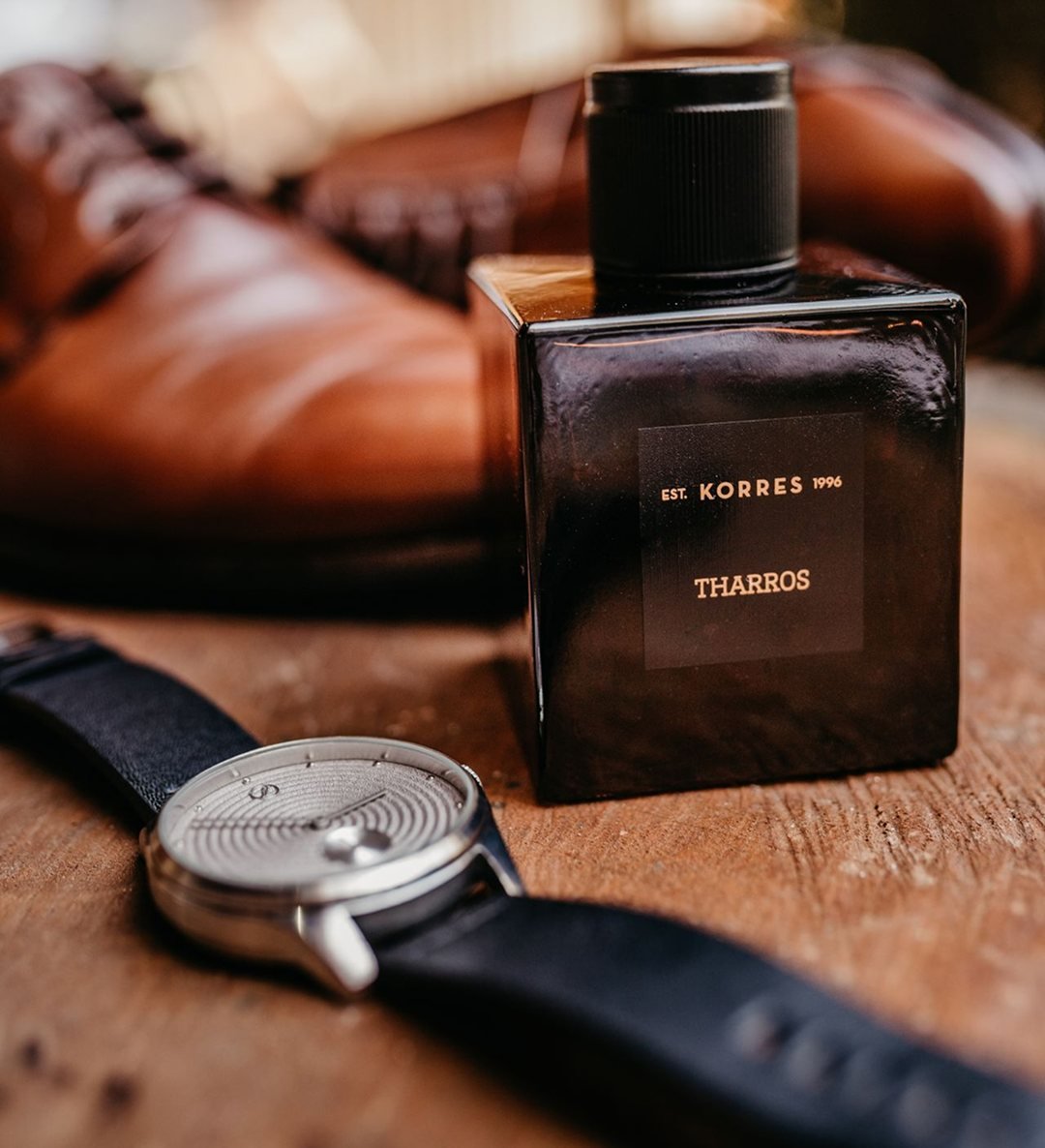 Perfume, relógio e sapatos de couro sobre madeira
